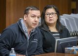 Alan Roy sits at the testifiers' table and speaks into a microphone to someone out of view. Representative Her sits next to him and watches as he speaks.